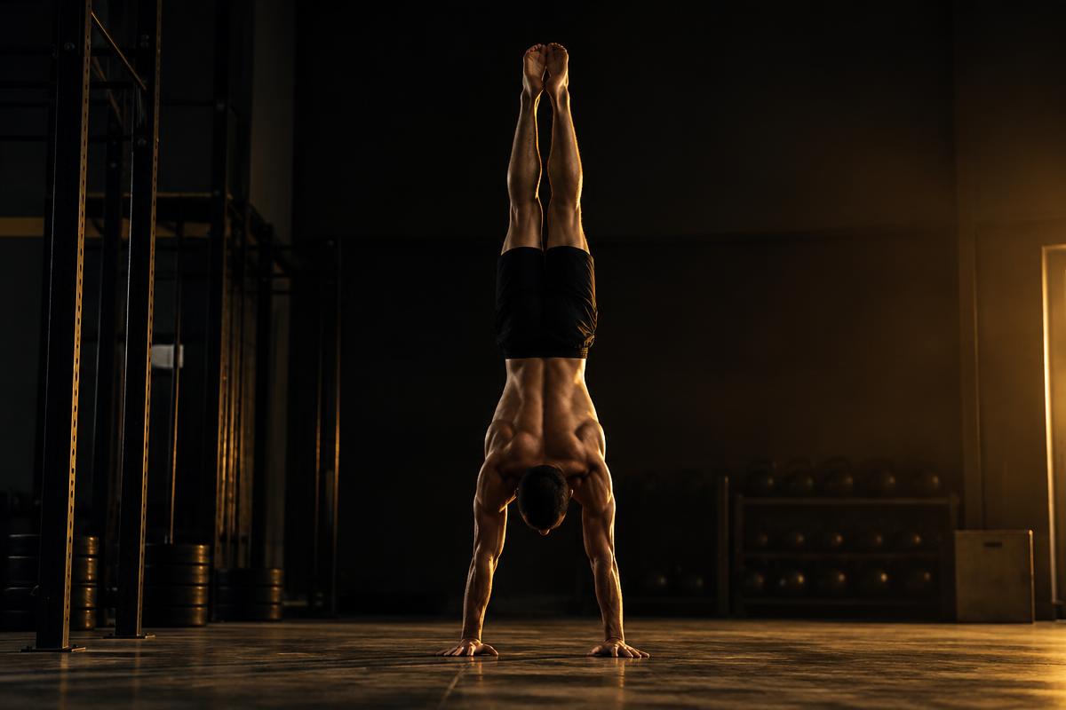 Athlete practising a handstand against a wall with straight arms and a hollow body line